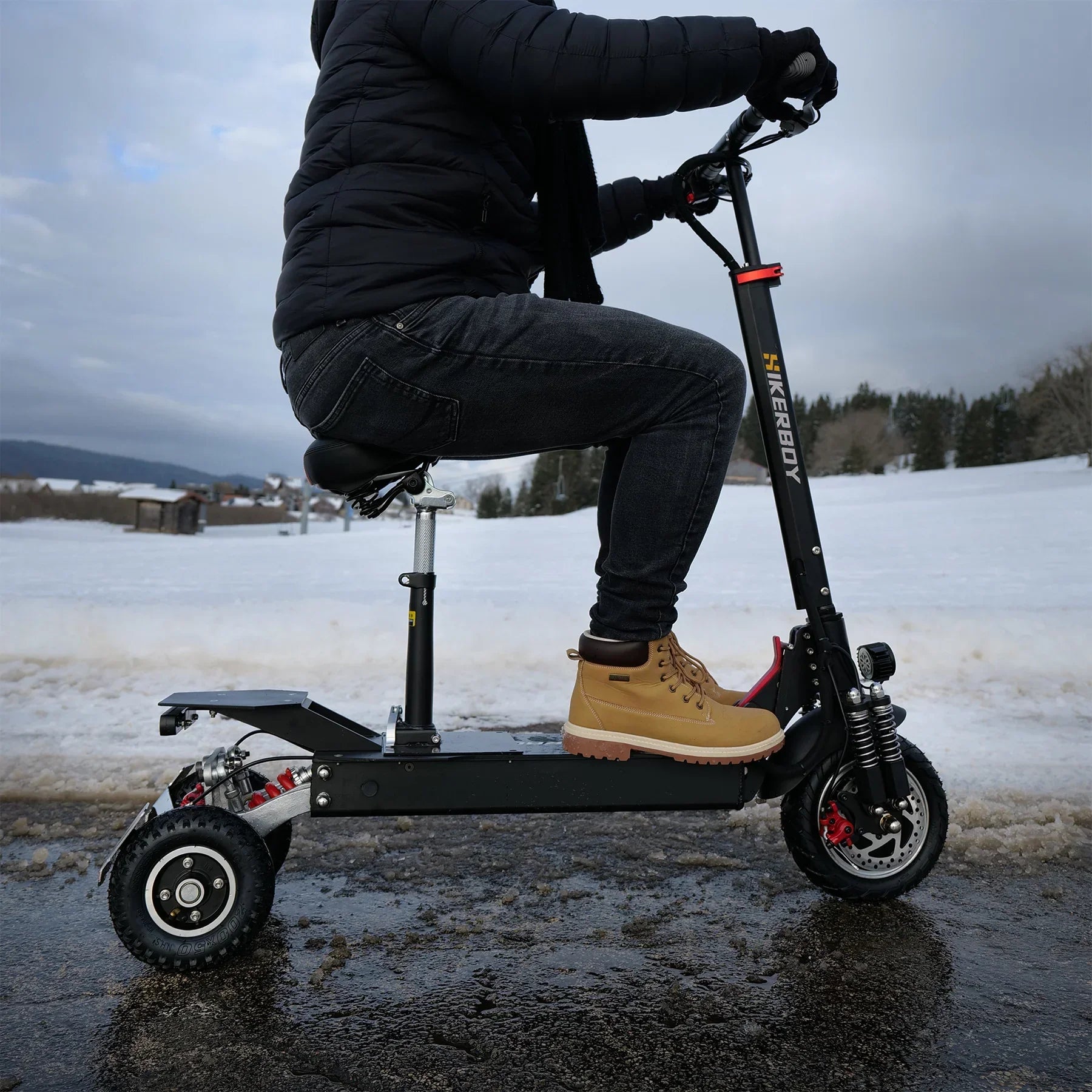 Person riding a black electric scooter in a snowy landscape