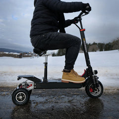 Person riding a black electric scooter in a snowy landscape