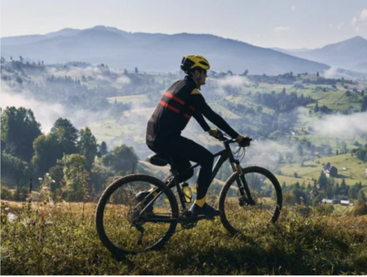 Electric mountain bike side view on countryside trail with cyclist and scenic hills