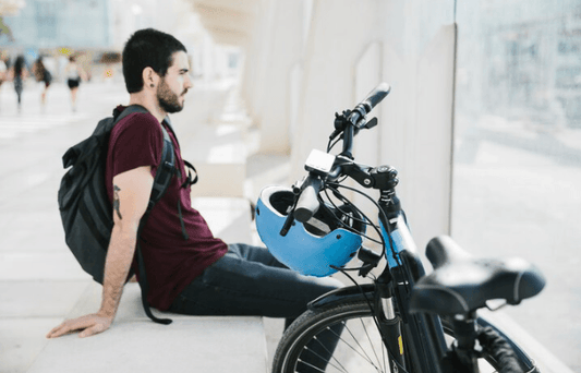 Man with backpack resting beside electric bike and helmet, e-bike store promo