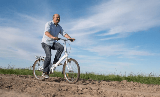 White electric bike ridden by senior man on a dirt path, side view in outdoor setting