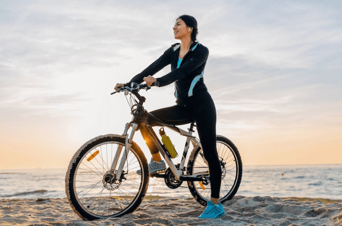 Woman riding a fat tyre electric bike on the beach at sunset from Pogo Cycles