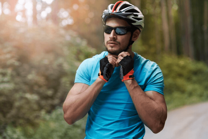 Man wearing a black and white cycling helmet and sunglasses preparing for e-bike ride outdoors